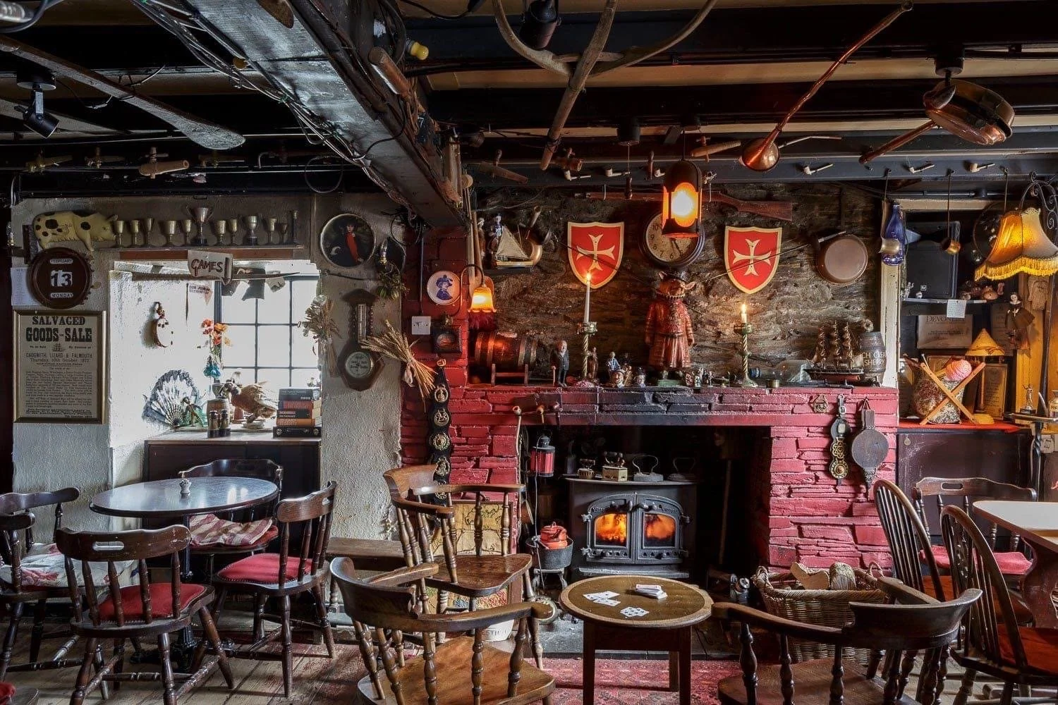 Pub room filled with wooden chairs, beams and eclectic objects