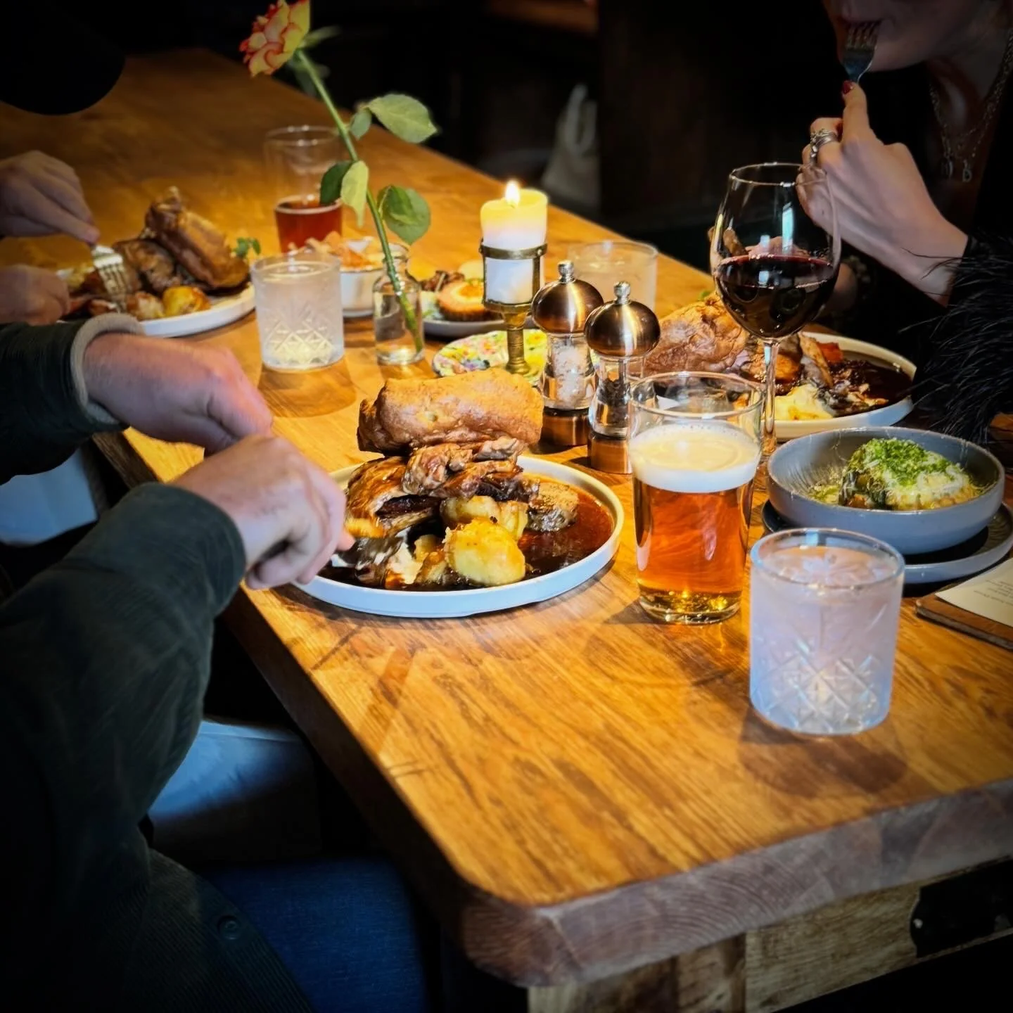 Friends sharing a meal and drinks around a wooden pub table