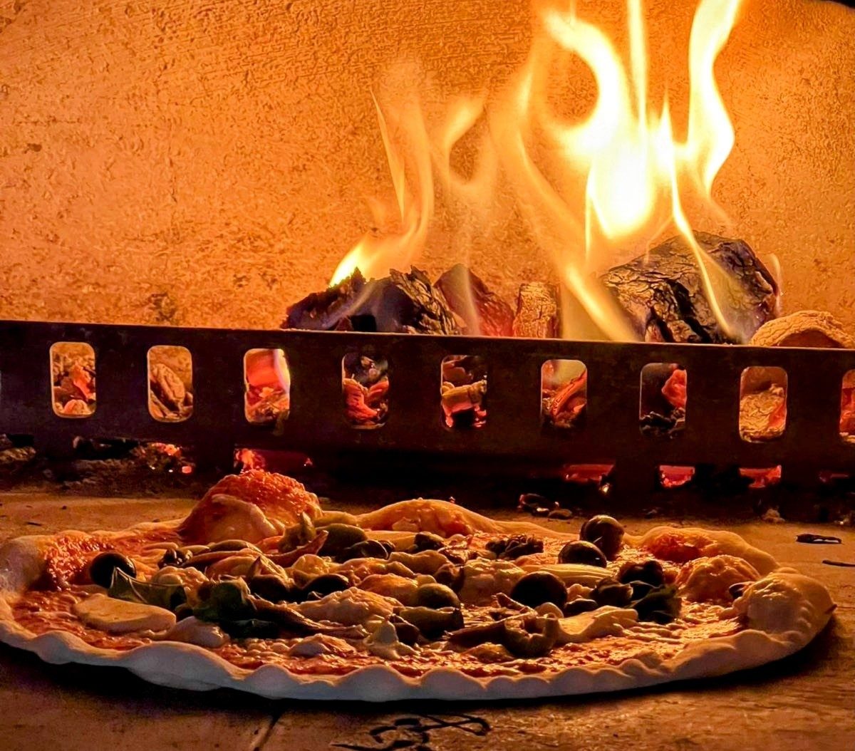 A pizza cooking beside the flames in Pizza Amore’s wood-fired oven