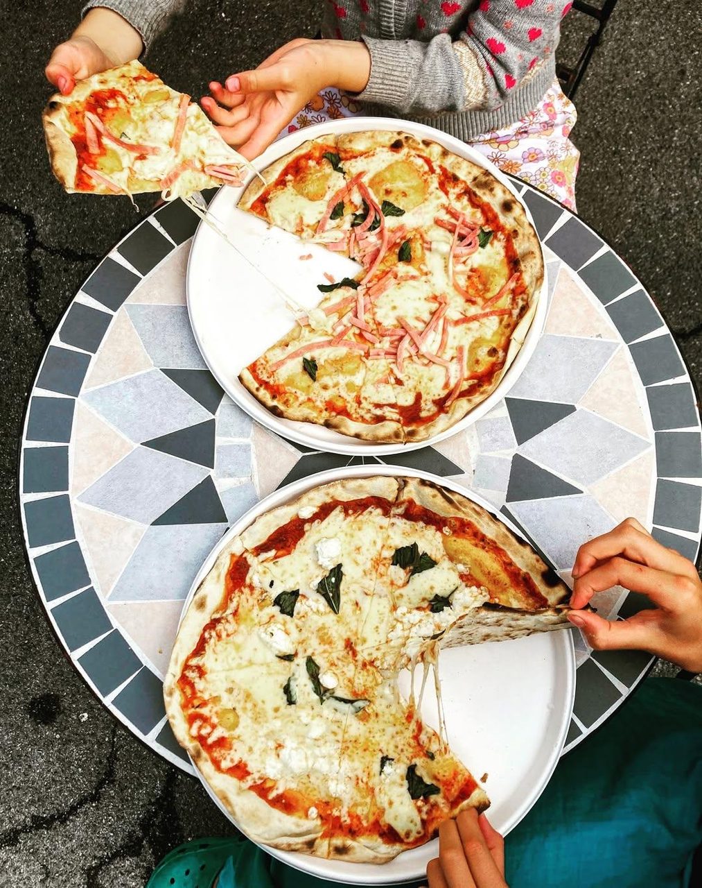 Pizzas shared around a patterned outdoor table at Pizza Amore