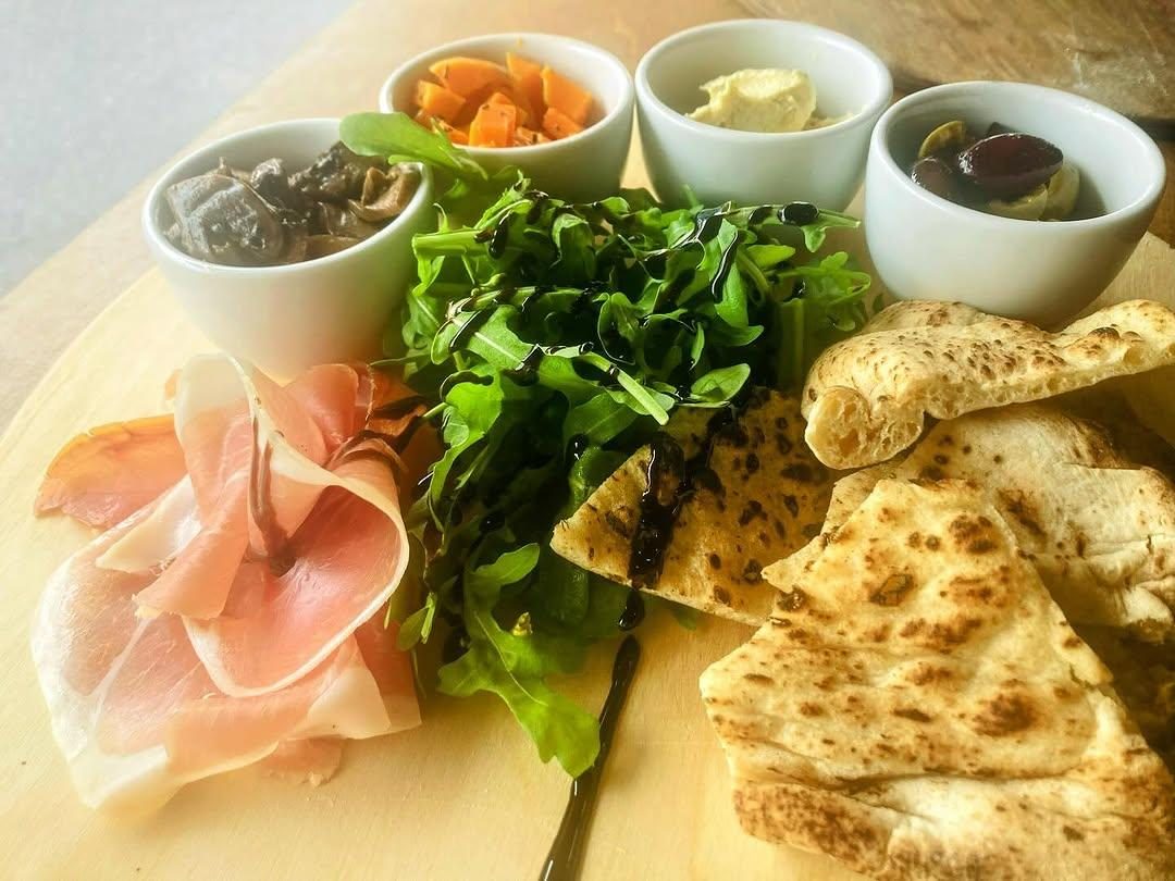 Antipasto, salad and flatbread with little bowls of toppings at Pizza Amore