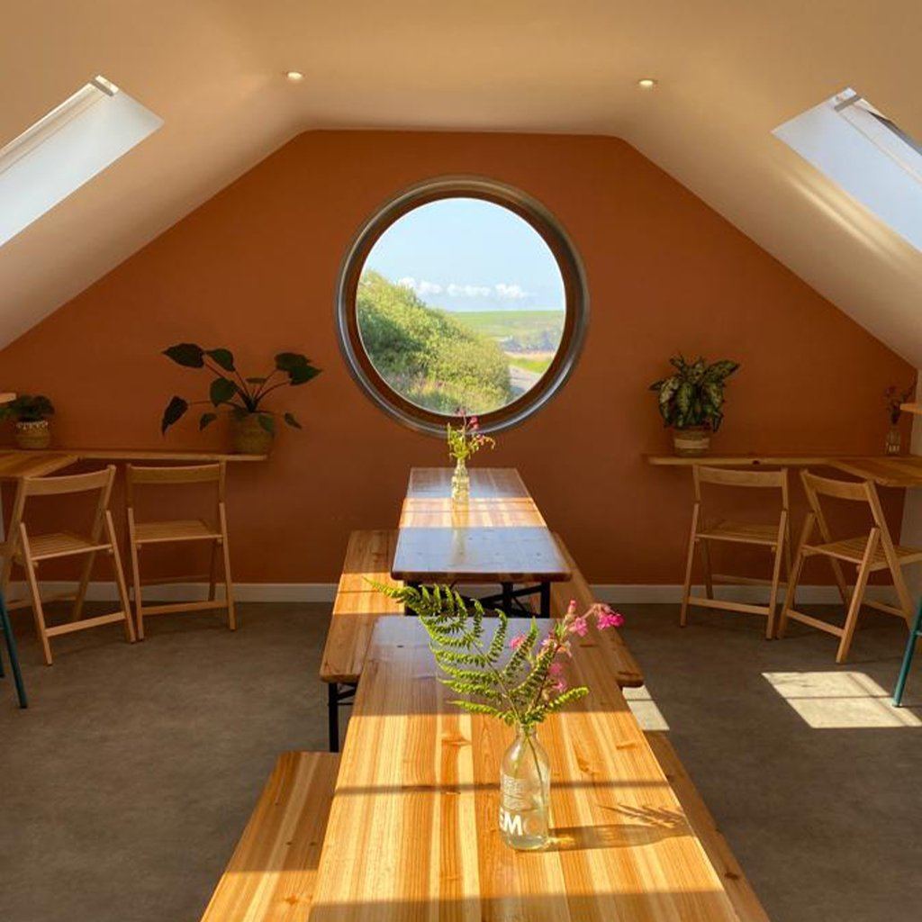 Round window and wooden tables upstairs at The Porthole