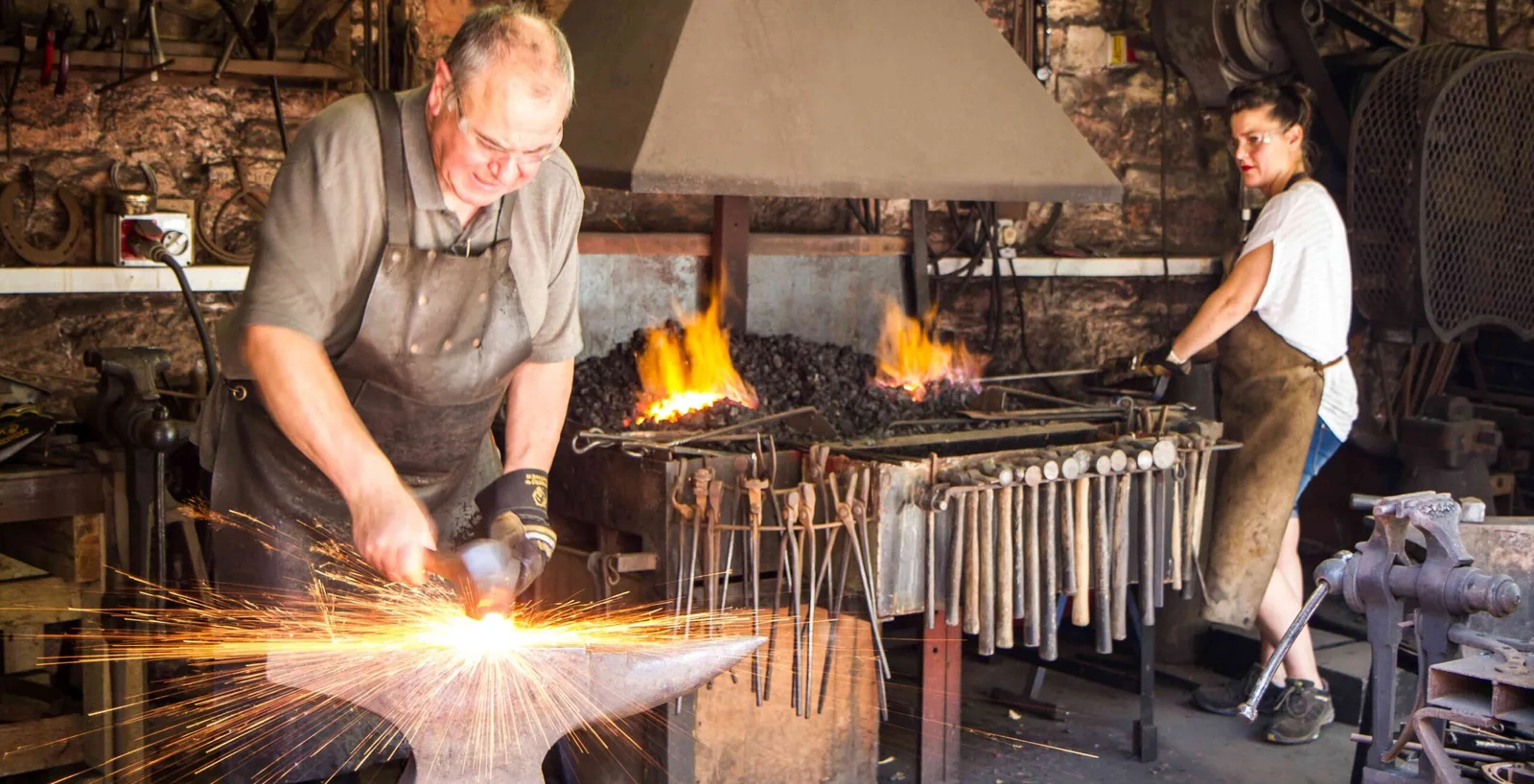 Rex and Katie Latham working beside the fire and anvil in the forge