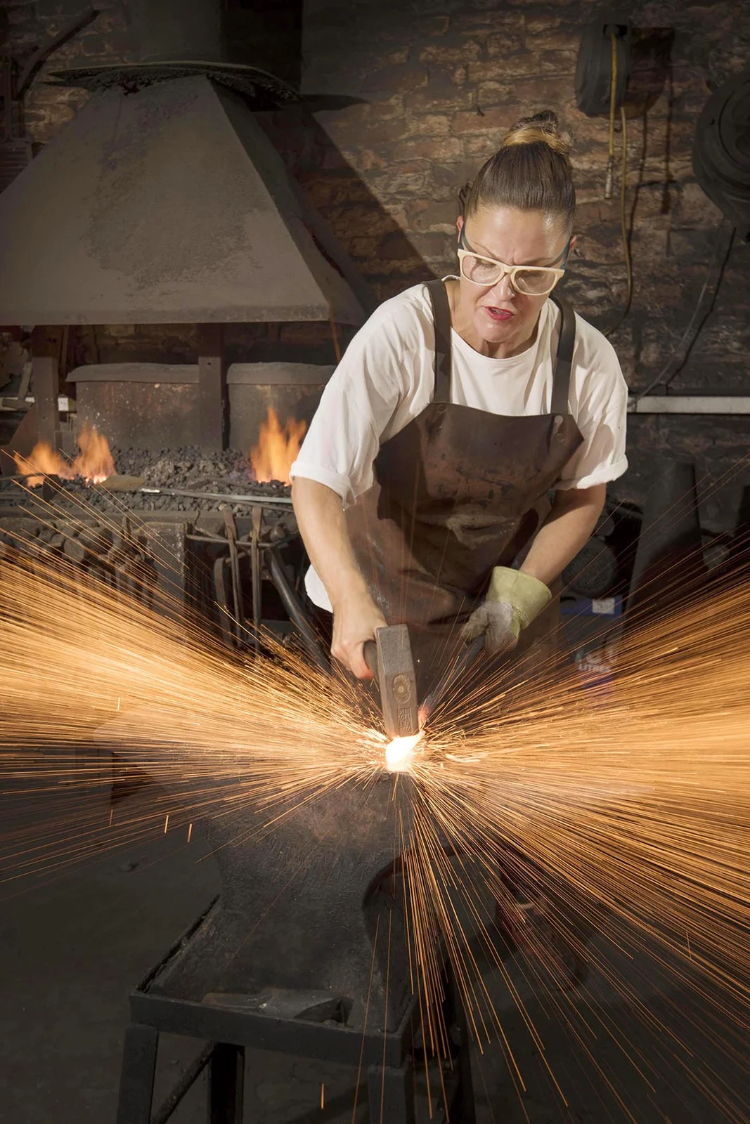 Katie Latham working metal with a shower of sparks