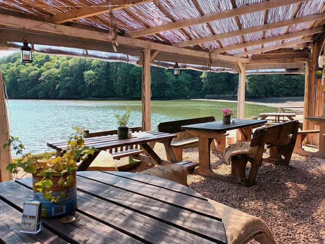 Covered wooden terrace tables overlooking the water at The River Shack