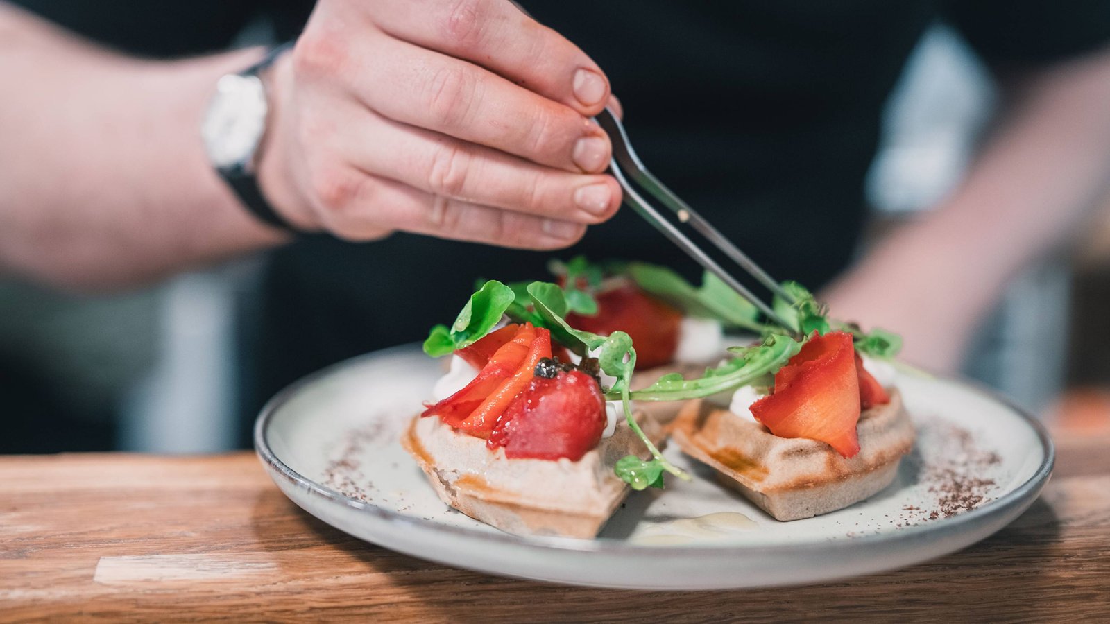 A chef finishing a plant-based brunch dish at Sacred Grounds