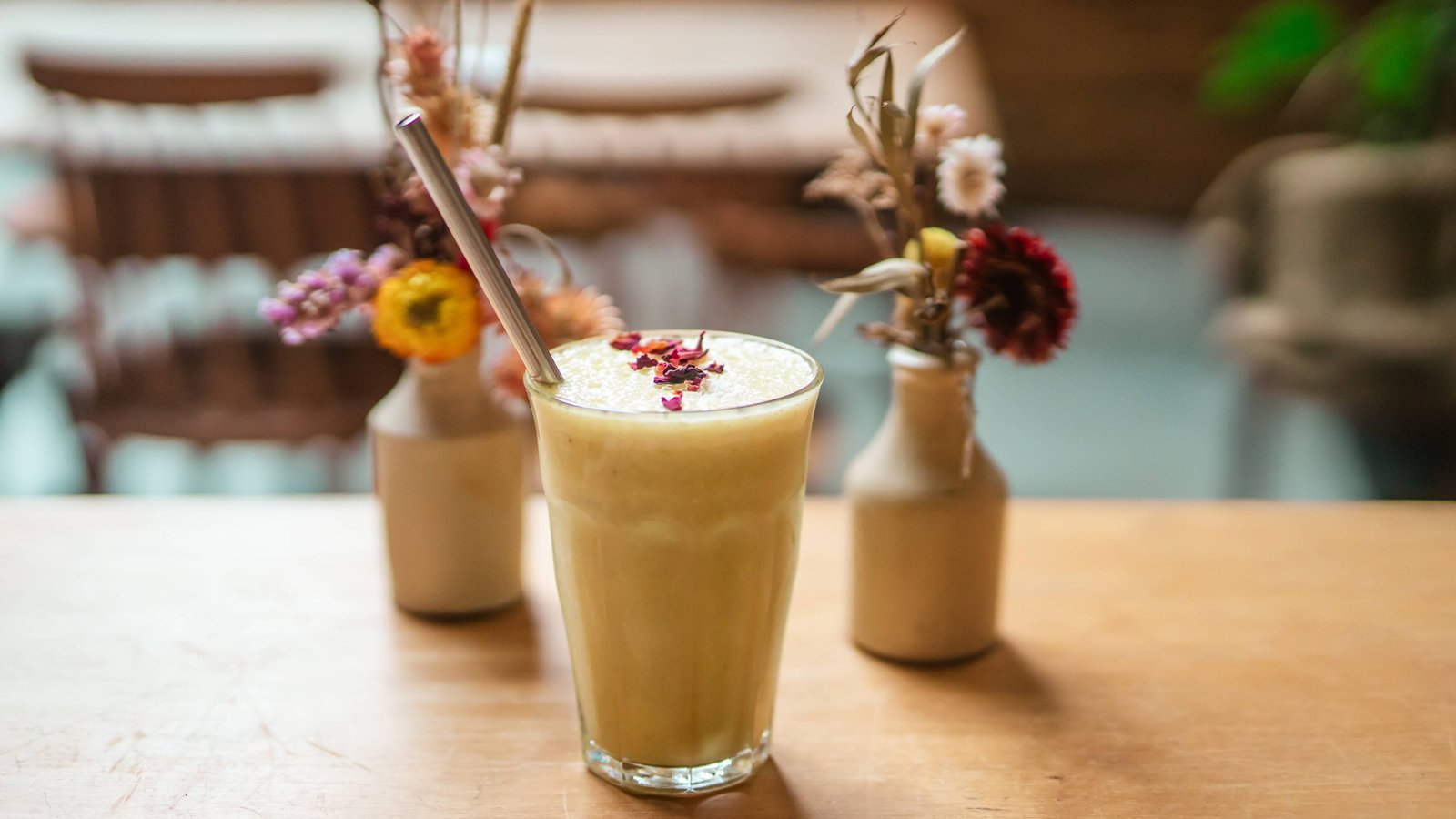 Two colourful drinks with straws and flower garnishes at Sacred Grounds