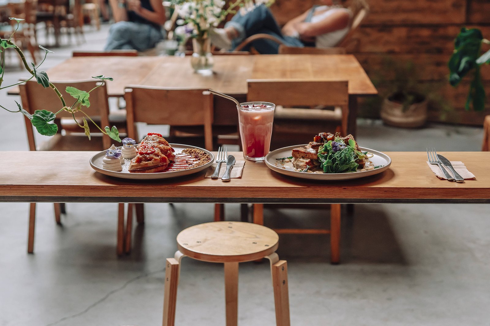 Brunch dishes on a wooden table beneath the Sacred Grounds arcade roof