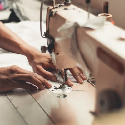 Hands guiding sailcloth through a sewing machine