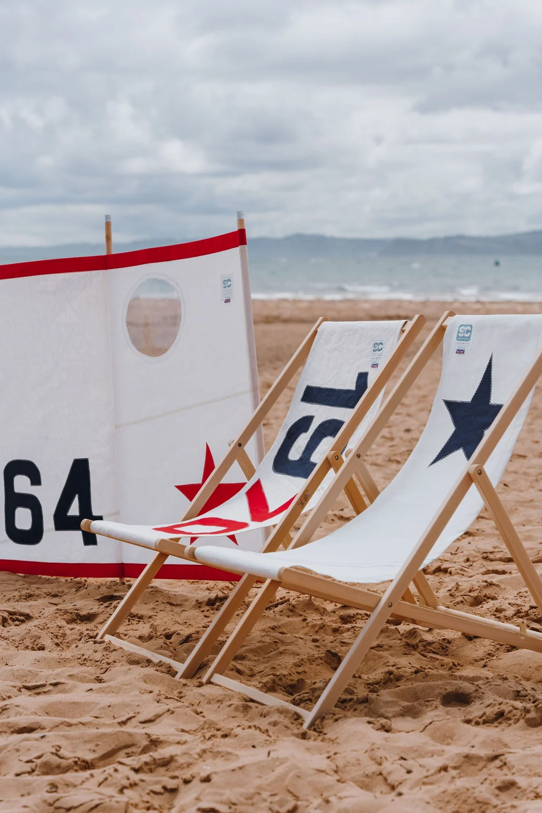 Two recycled sailcloth deckchairs on a beach