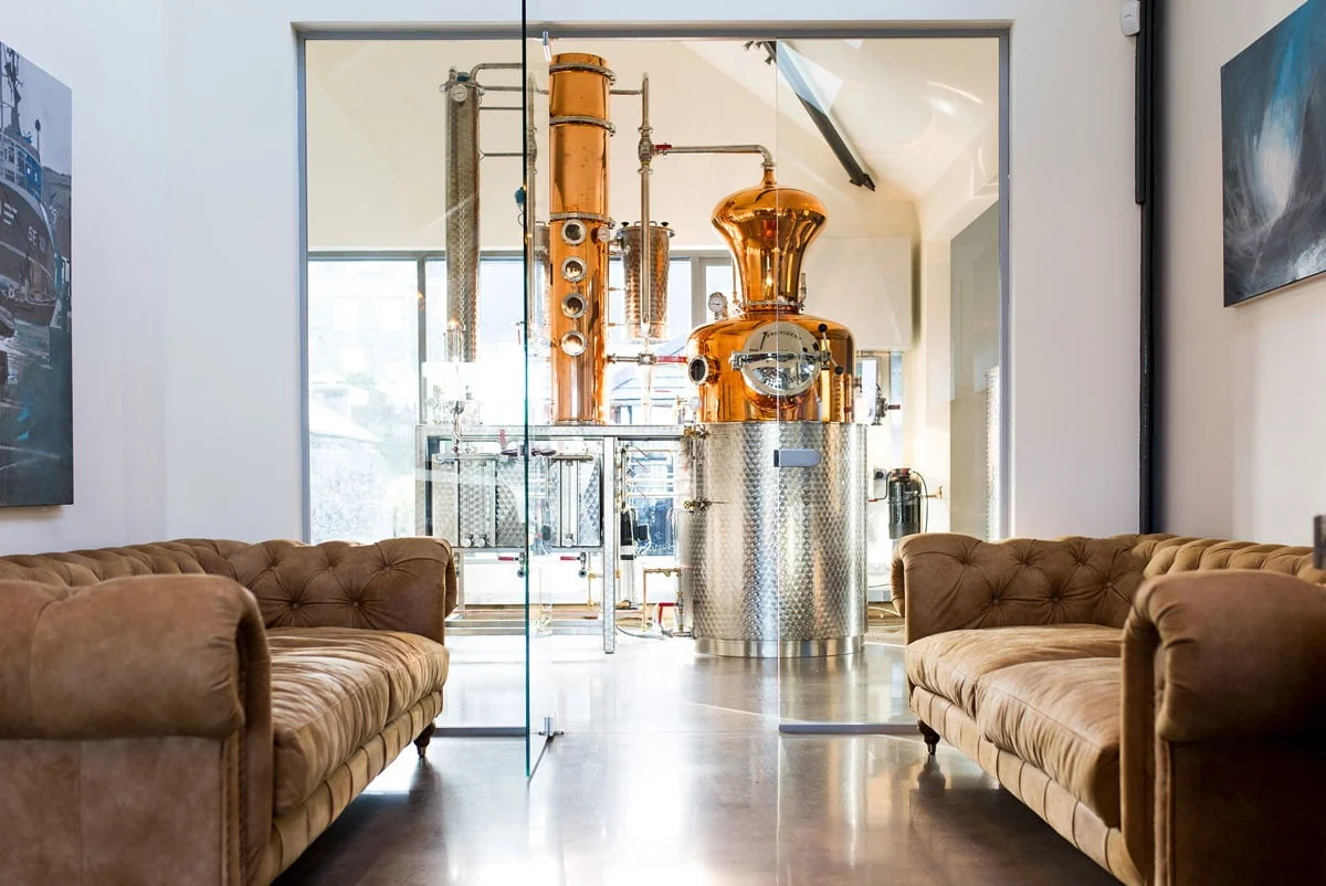 Leather sofas in the distillery bar beside a large copper still