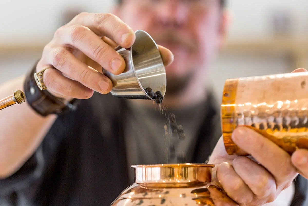 Liquid being measured into a miniature copper still