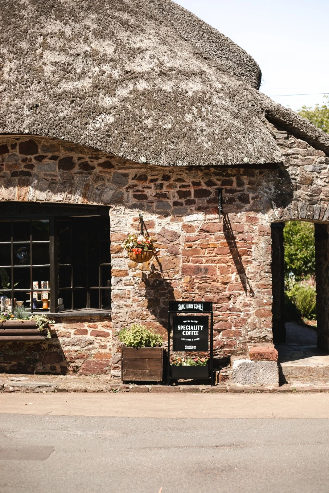 Thatched stone building housing Sanctuary Coffee in Cockington