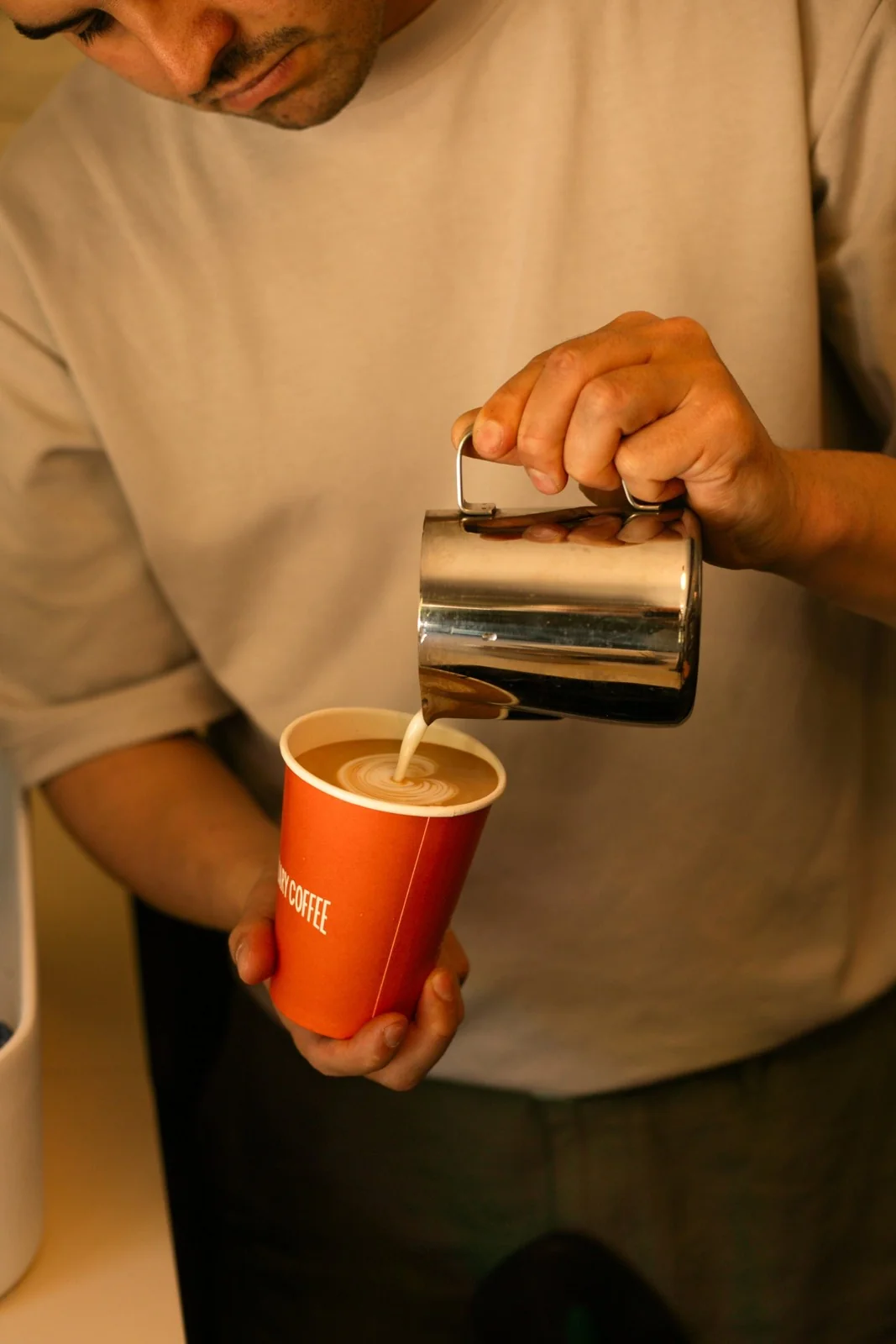 Milk being poured into a Sanctuary takeaway coffee