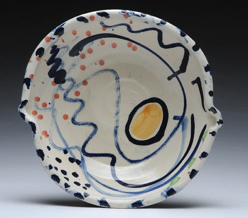 A hand-painted ceramic plate with flowing blue lines and colourful spots by Sandy Brown