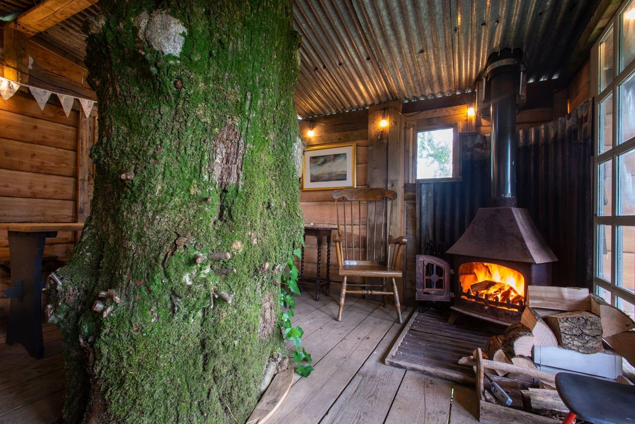 A covered wooden seating area with a glowing wood burner