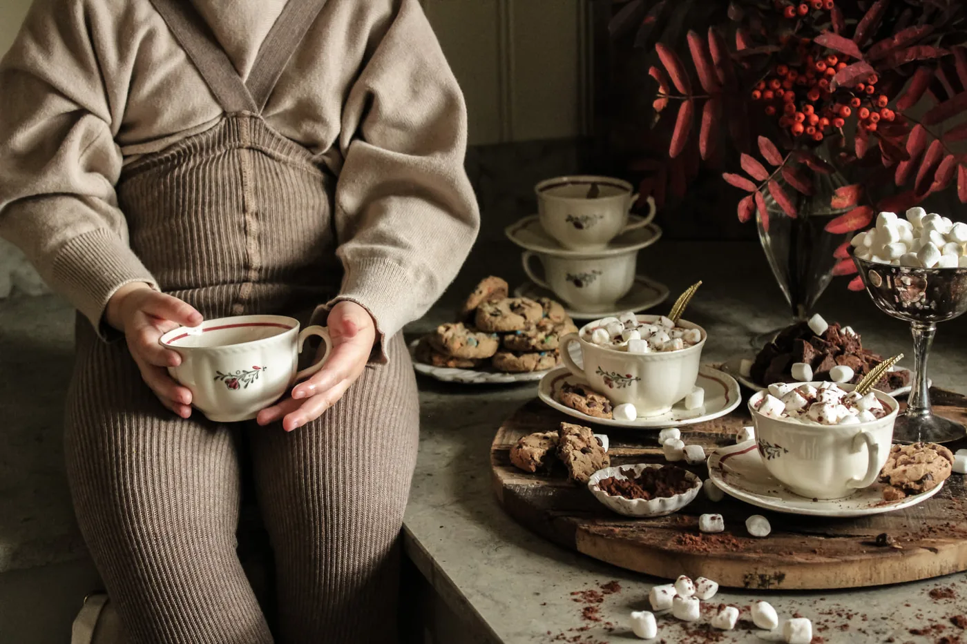 Child wearing knitted tights beside a tea table in a Silly Silas collection photograph