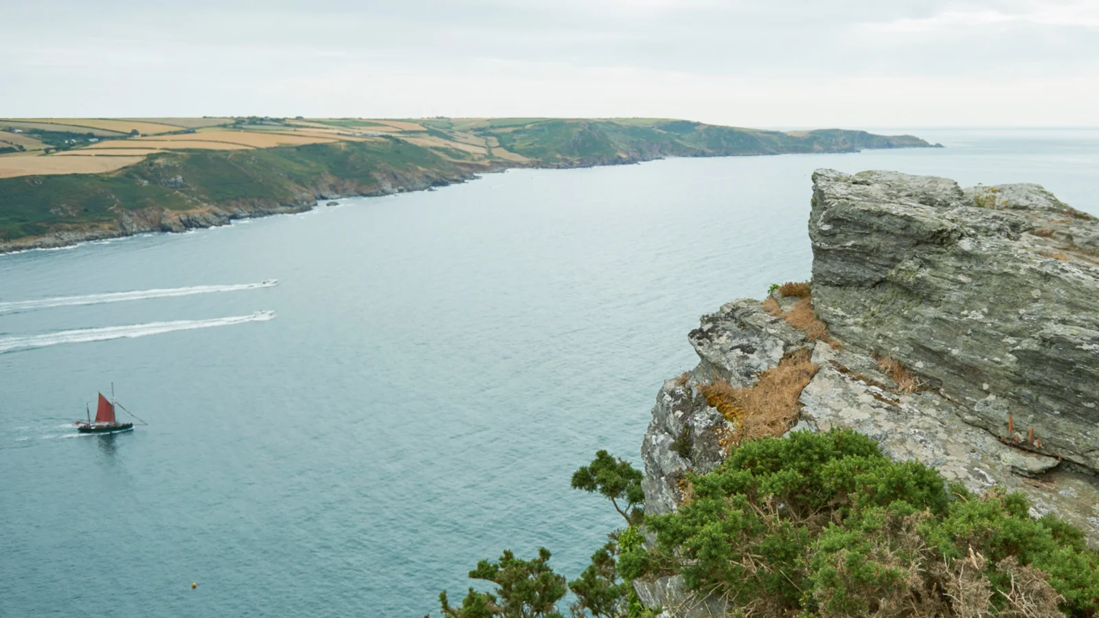 Small sailing boat beside the rugged East Soar coastline