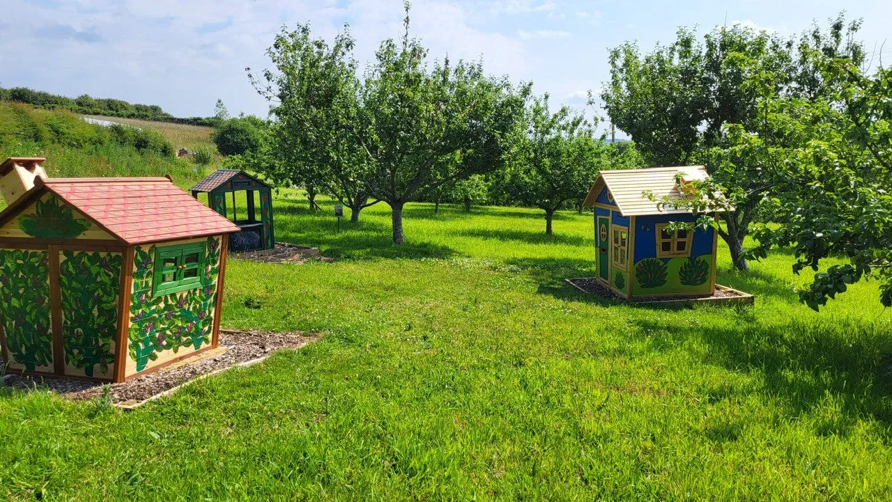 Small colourful playhouses in the farm’s grassy play area