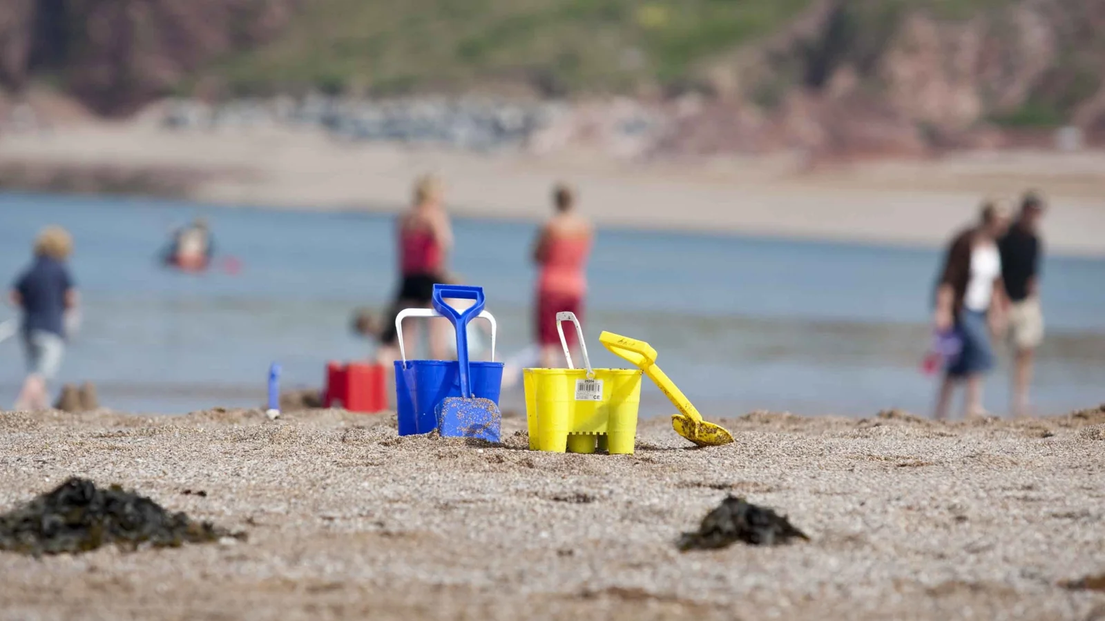 Colourful buckets and spades on the sand near the water