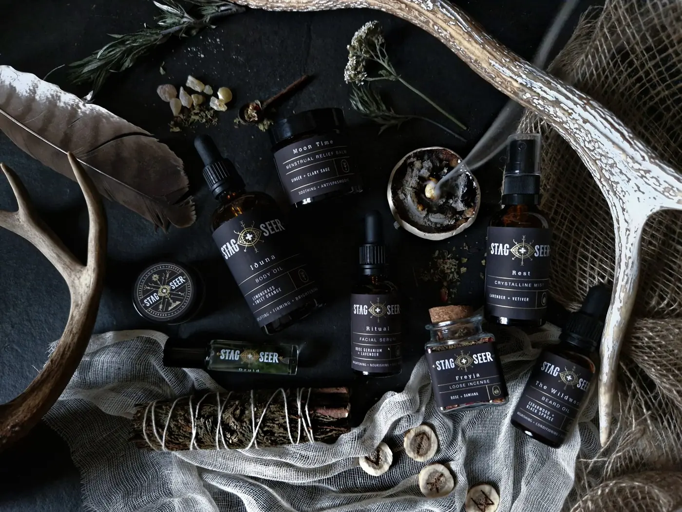 Dark glass Stag + Seer bottles and botanical objects arranged on fabric