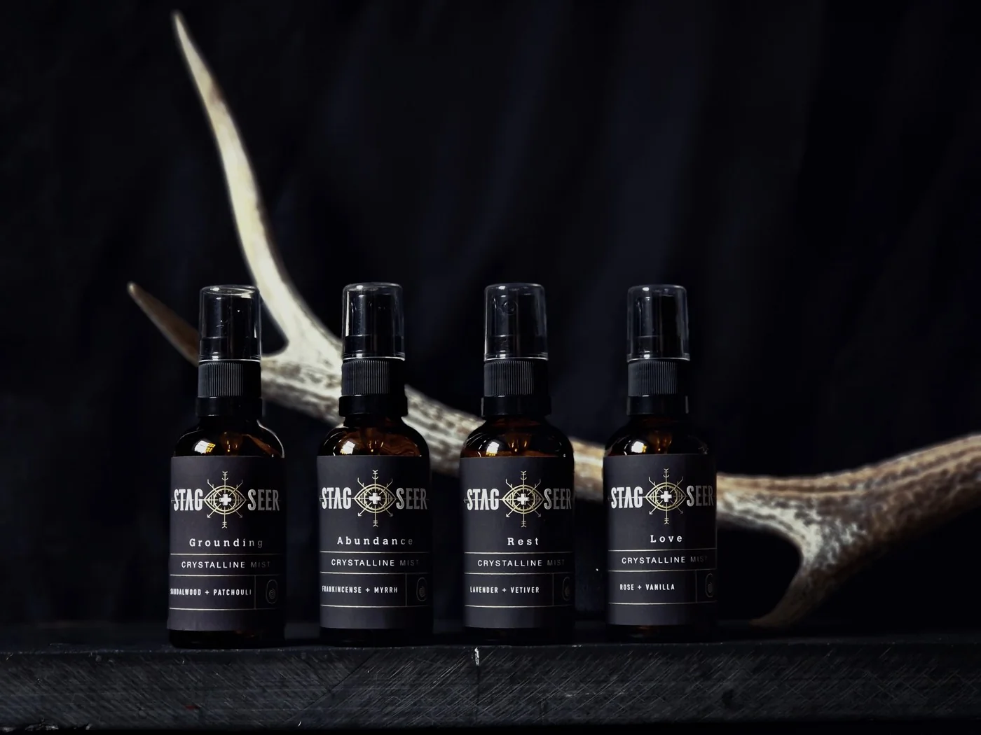 A row of Stag + Seer mist bottles against dark fabric