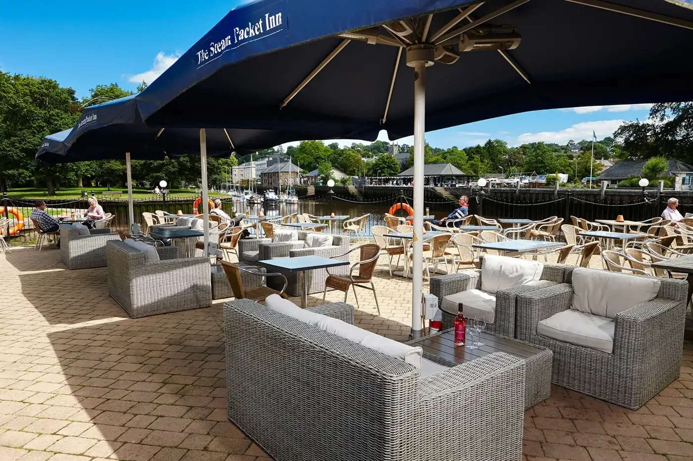 Sofas and tables beneath a parasol on The Steam Packet Inn’s riverside terrace