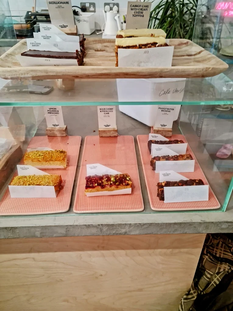 Cakes and brownies displayed on pink trays behind glass