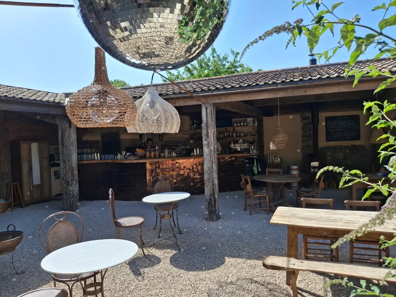 Courtyard seating beneath woven lampshades and a mirror ball