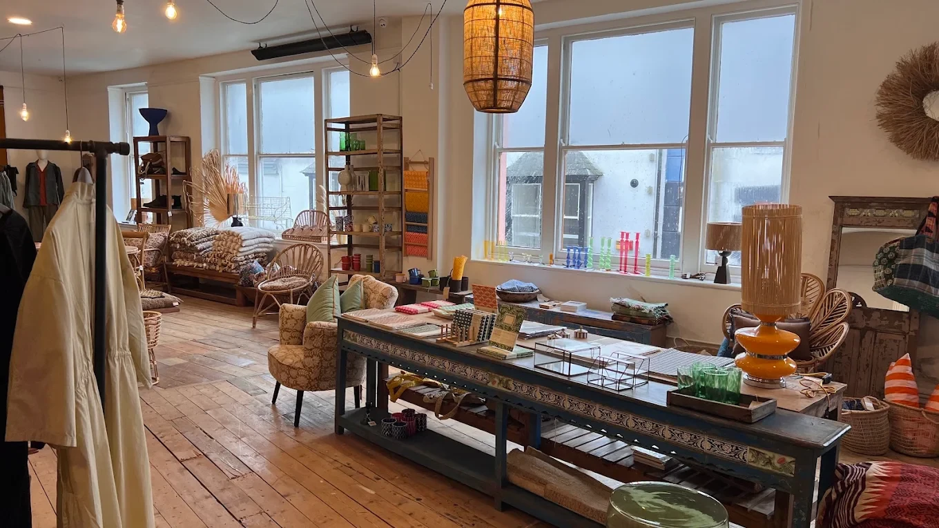 Homeware, woven chairs and glassware beside tall shop windows