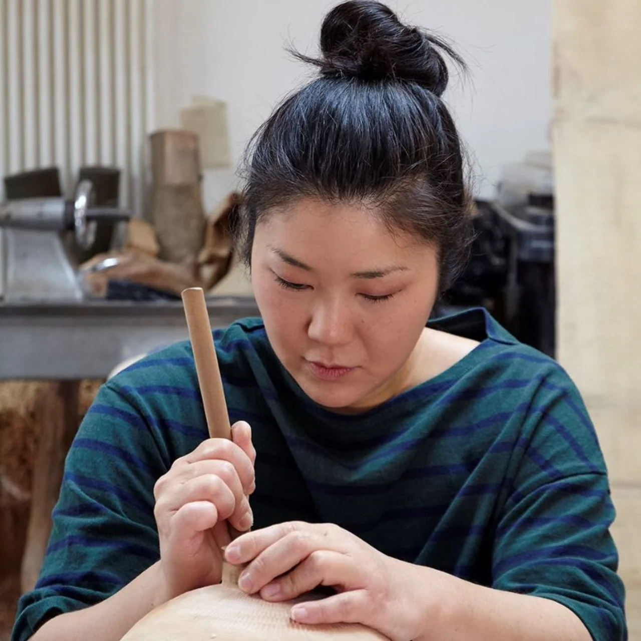 Kaori Takahashi carving a wooden object at her workbench