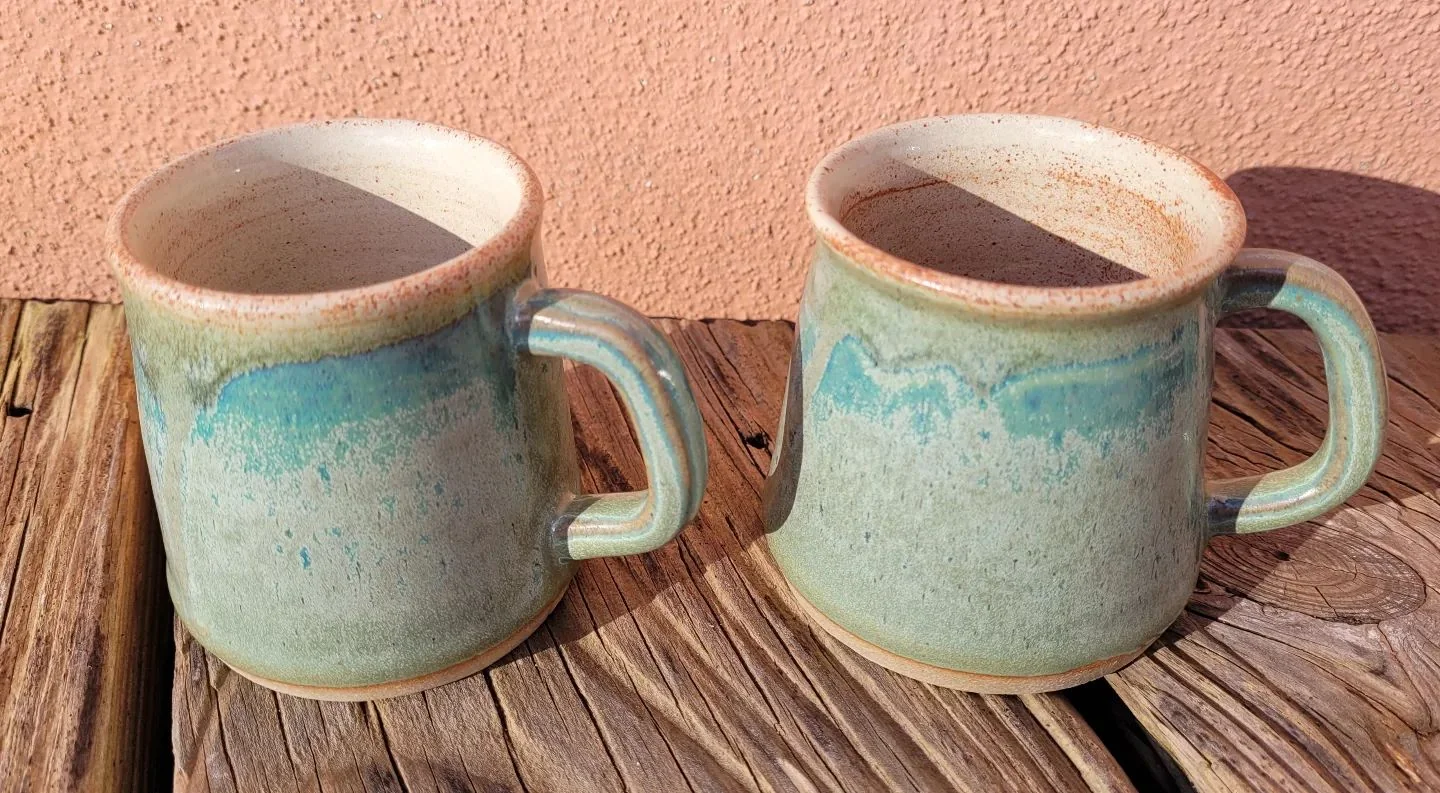 Two handmade turquoise and cream ceramic mugs