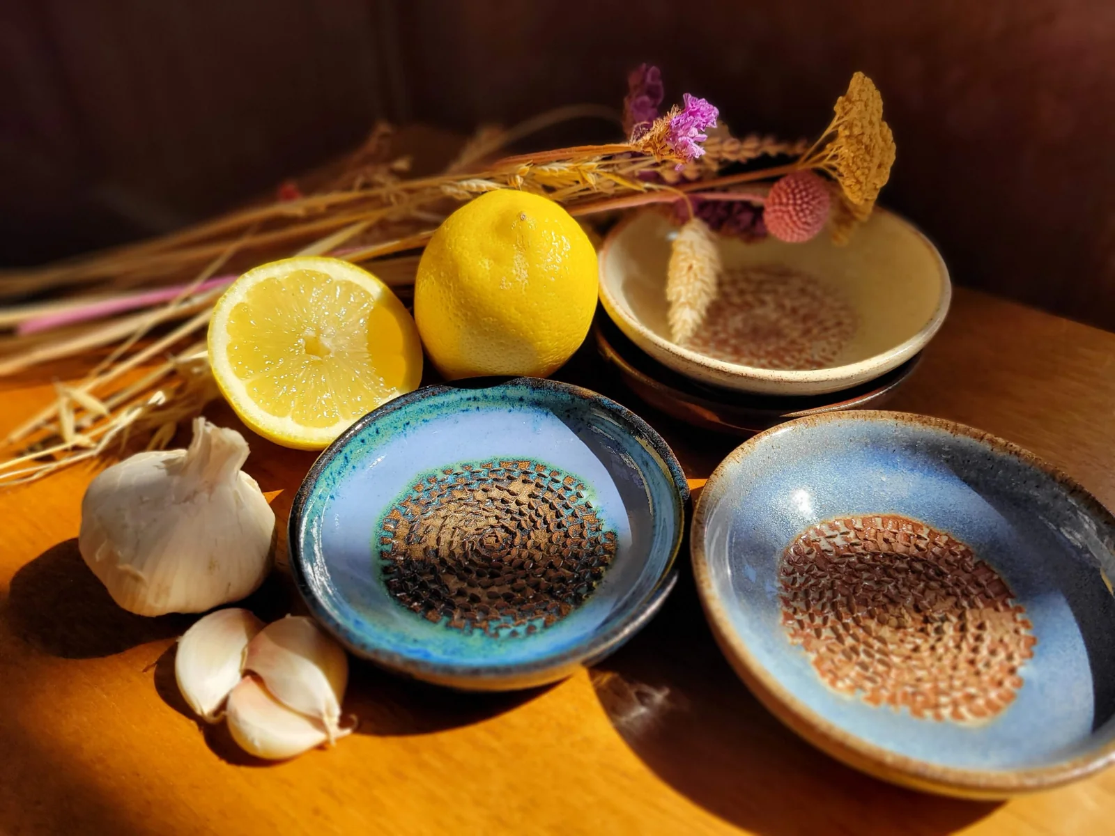 Glazed ceramic garlic and ginger graters beside lemons and garlic