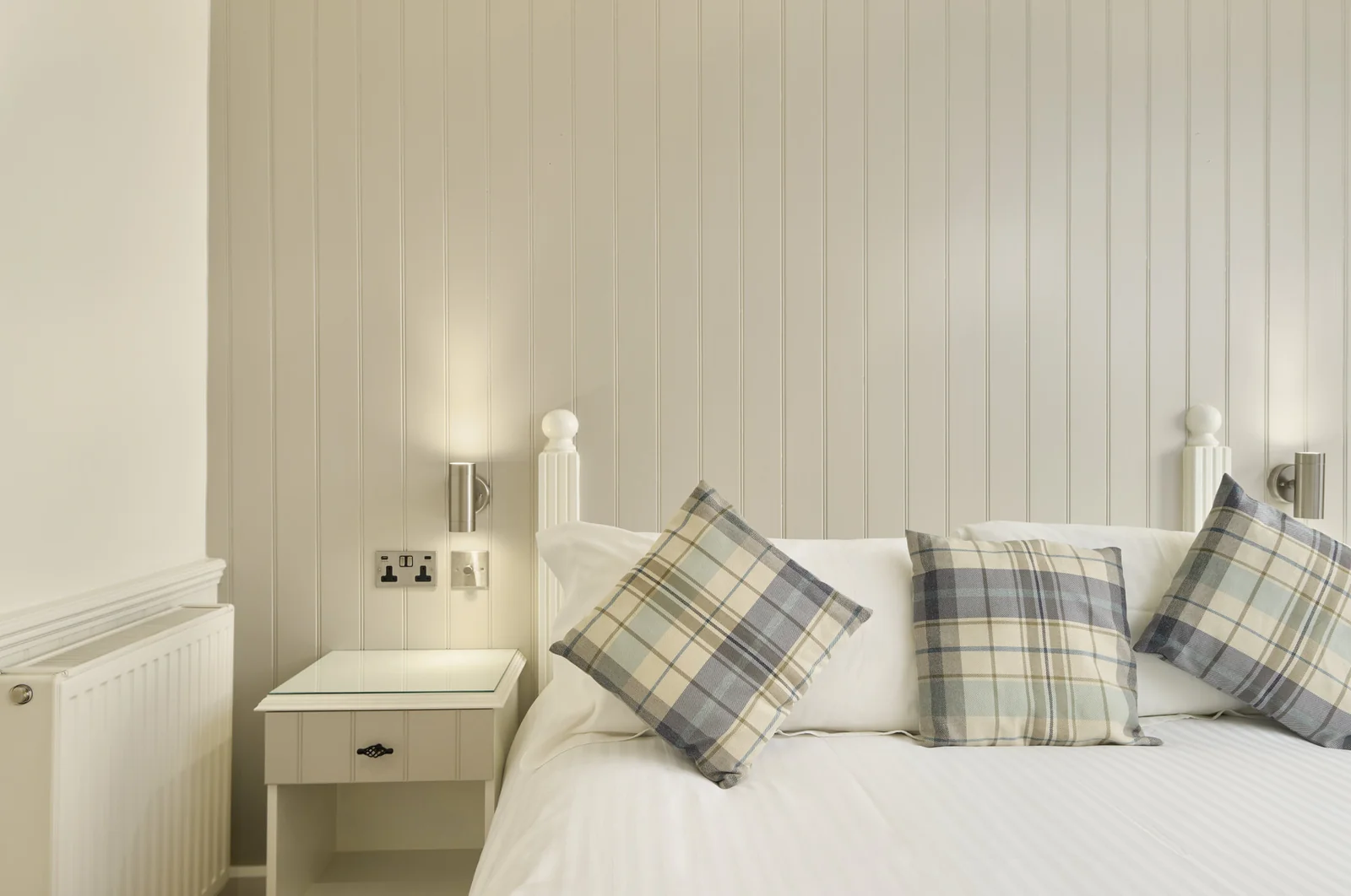 A pale panelled bedroom with a double bed at The Cricket Inn