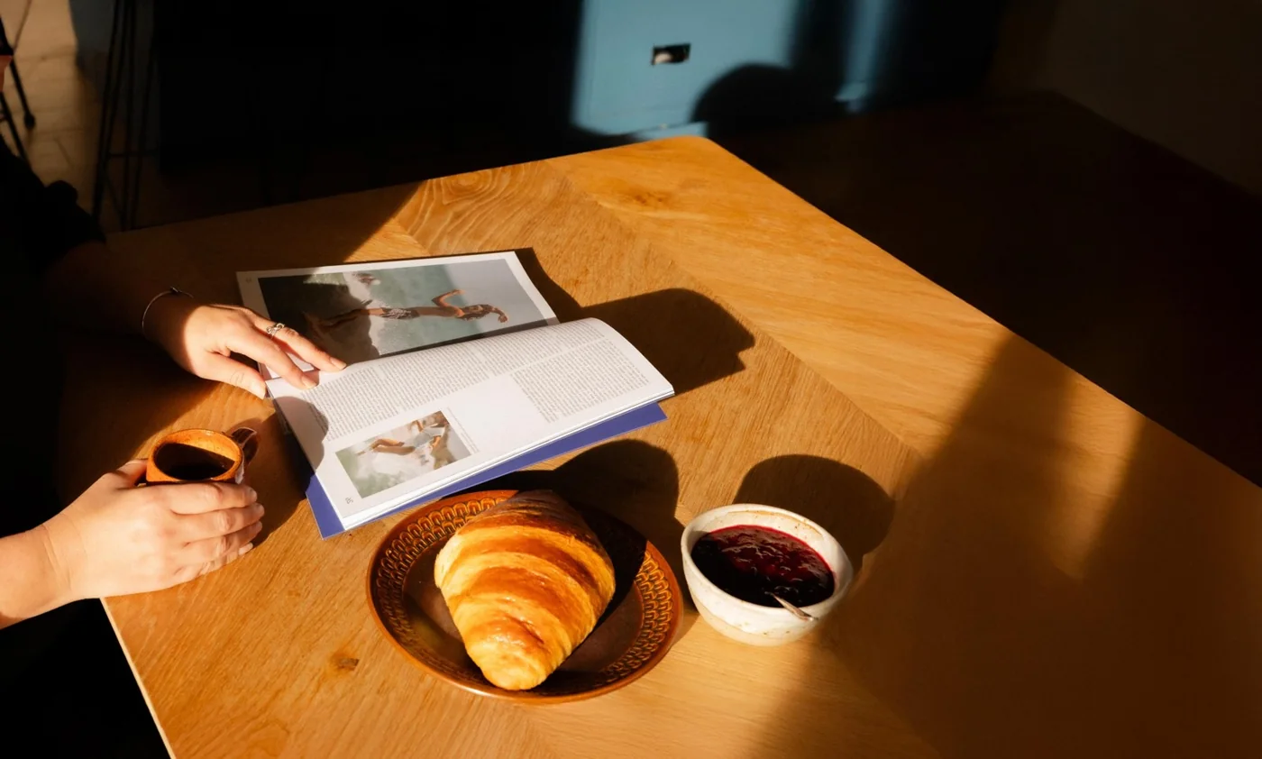 Coffee, a pastry and an open magazine on a sunny table