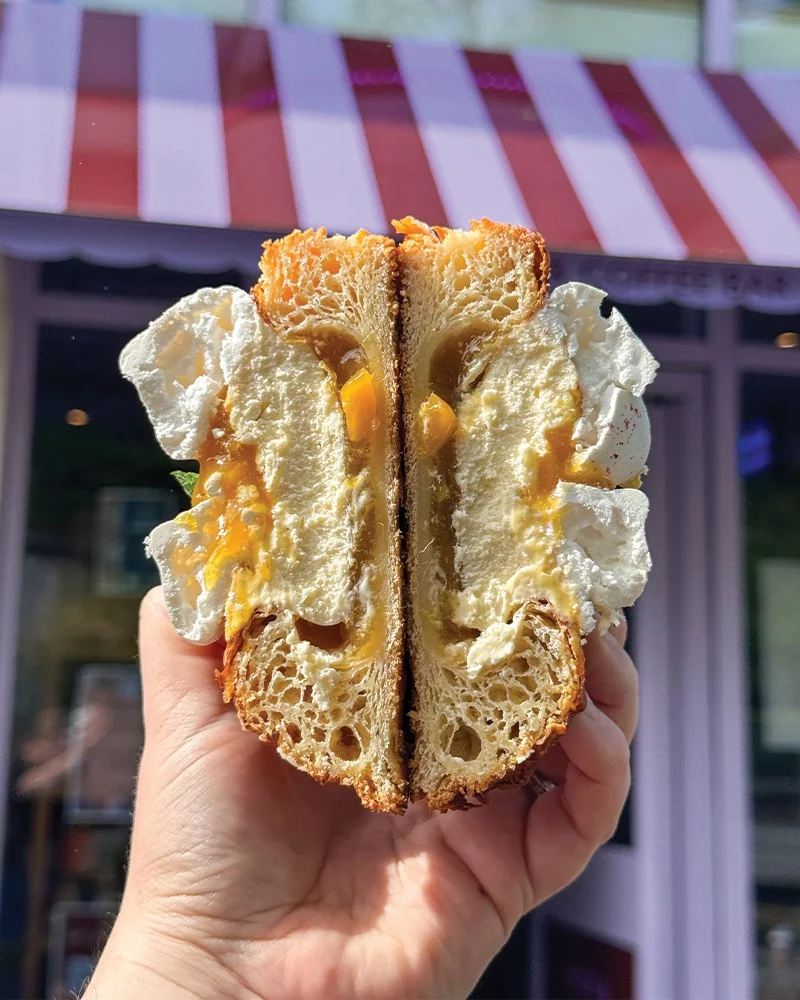 A filled bread roll held outside The Daily Knead’s striped awning