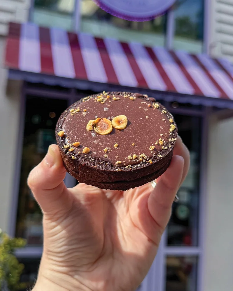 A chocolate-topped pastry held outside The Daily Knead