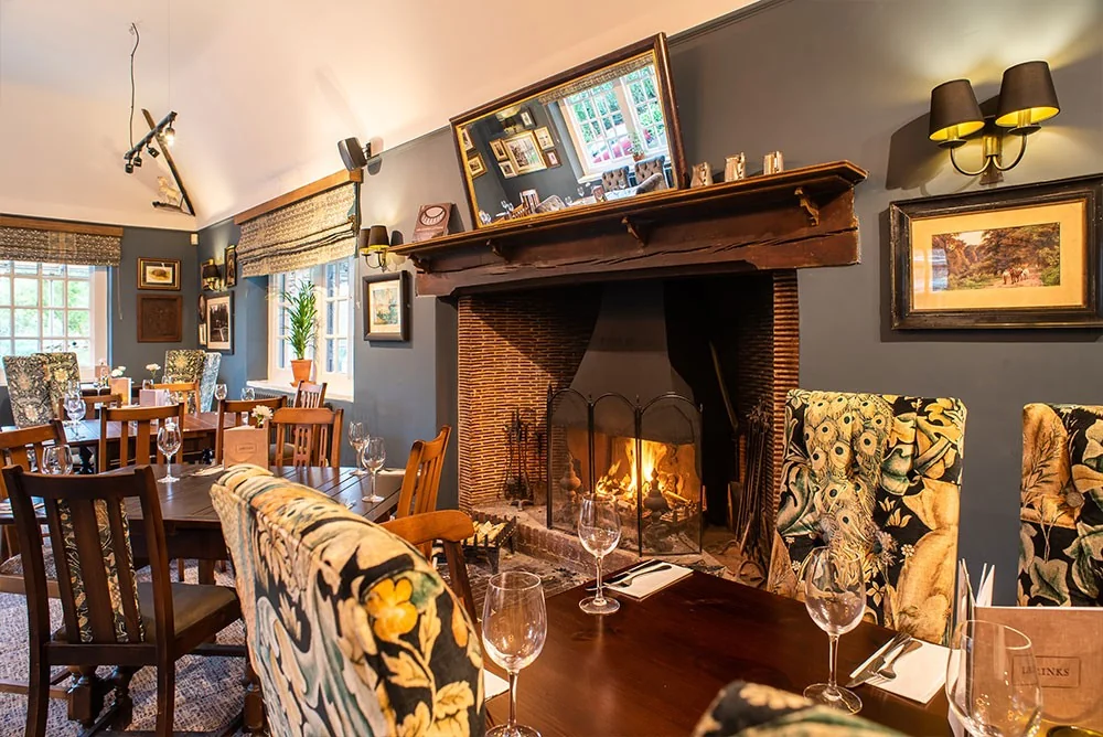 Armchairs beside a lit fireplace at The Drum Inn