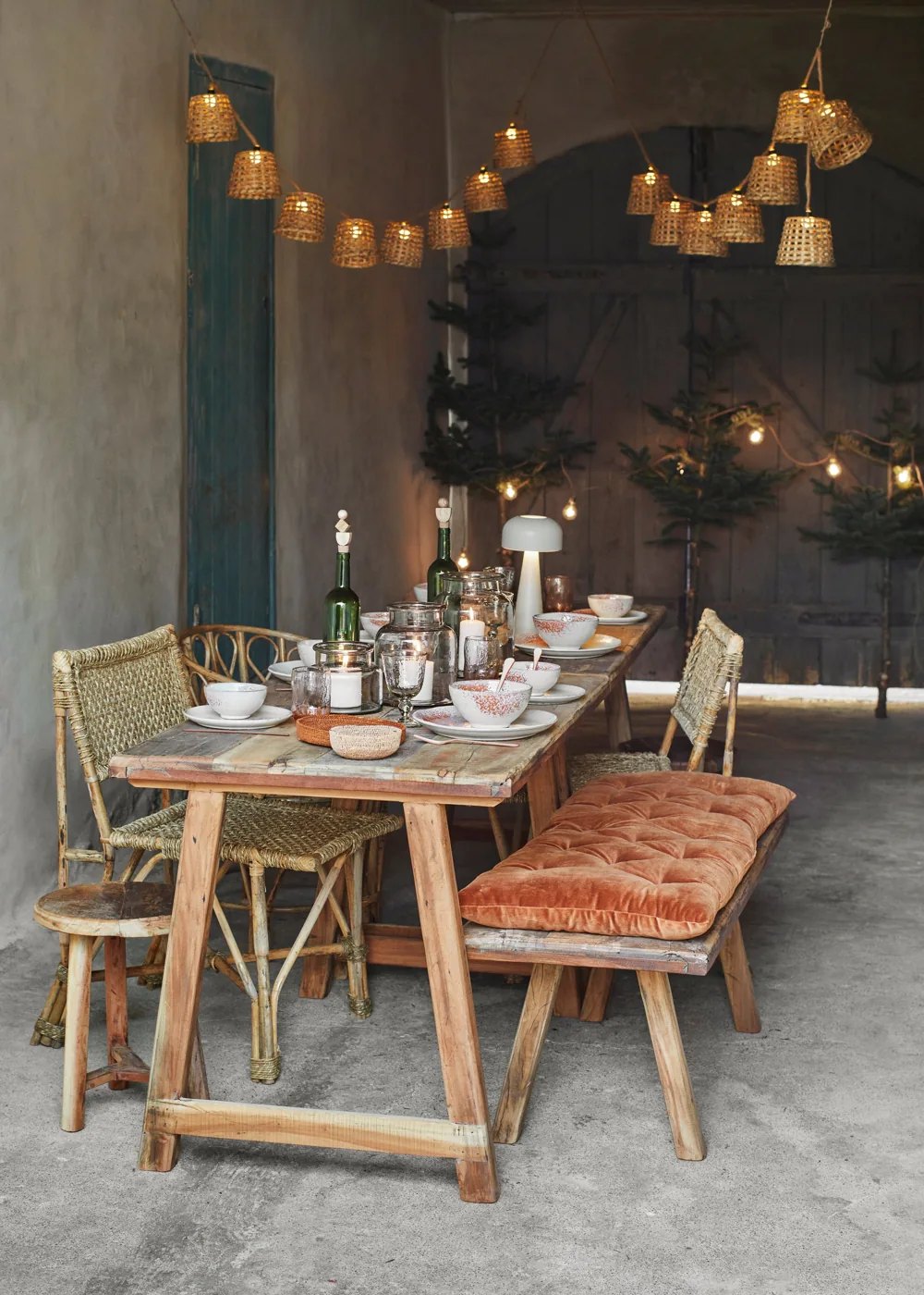Dining table beneath bamboo shade string lights in an official product styling photograph