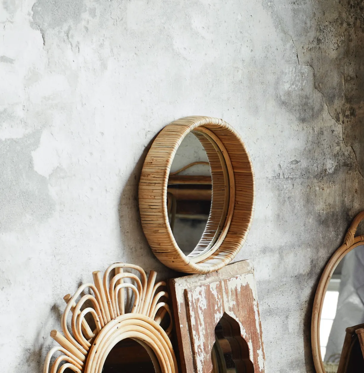 Woven mirrors arranged against a textured wall in a product styling photograph
