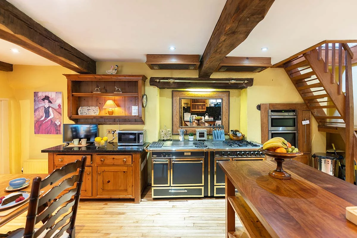 Timber kitchen cupboards, a black range cooker and exposed ceiling beams