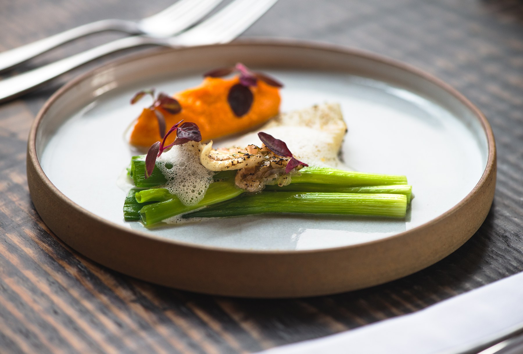 A colourful plated dish on a wooden table at The Old Library in Ashburton.