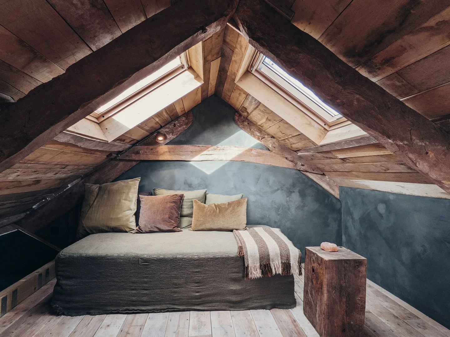 Cushioned mezzanine nook beneath roof beams and a skylight