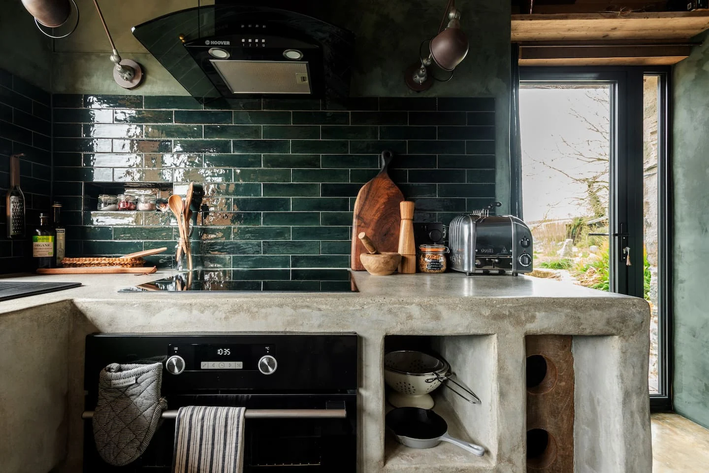 Hand-built kitchen with dark green tiles and concrete surfaces