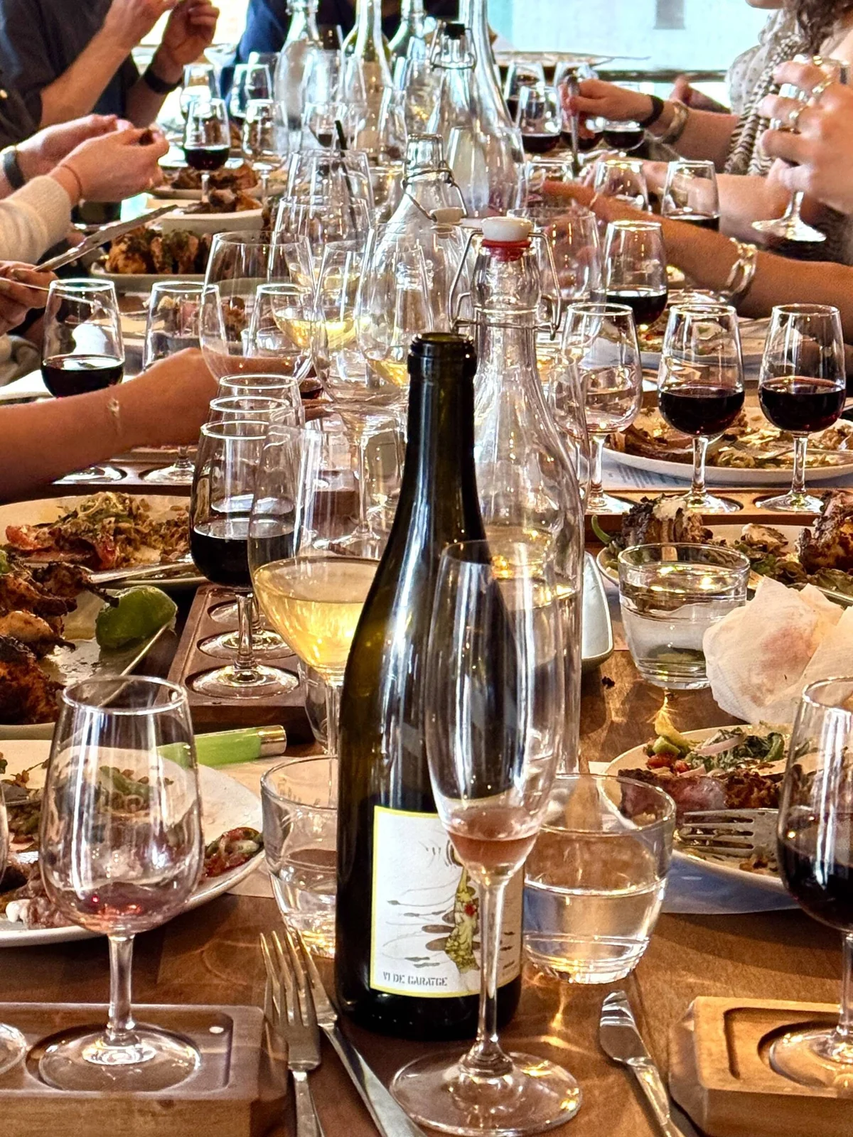 A long table set with wine glasses and bottles during a tasting