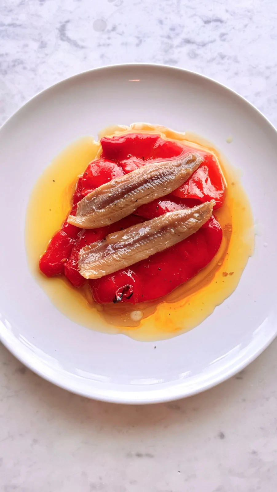 A small plate with anchovies and red peppers