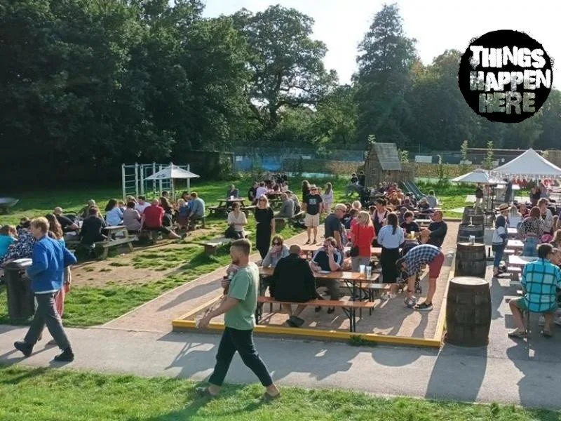 Visitors at sunny outdoor tables beside Things Happen Here at Meadowbrook