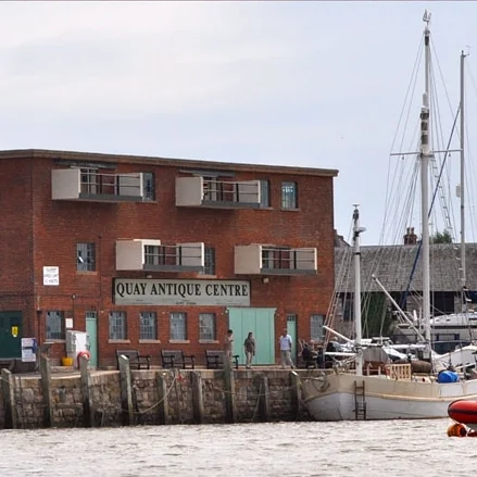 Riverside view of the brick antiques warehouse and a moored sailing boat