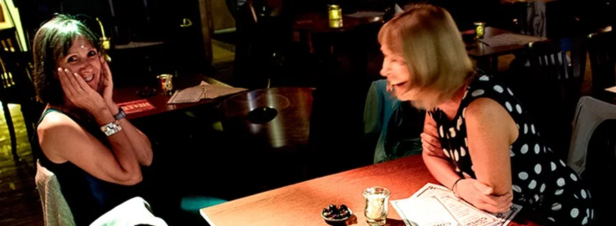 Two visitors chatting over drinks at a table inside Totnes Cinema