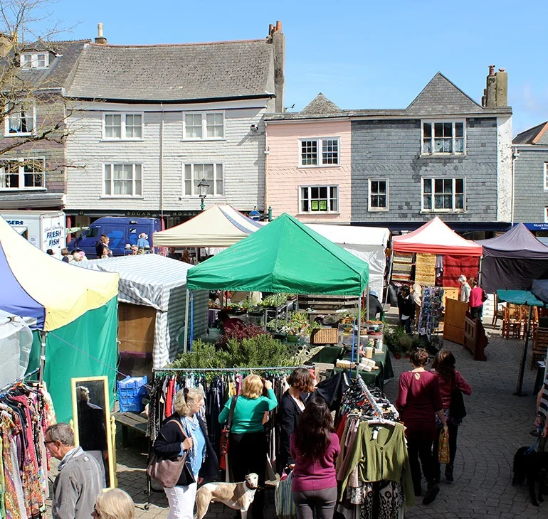 People shopping between green market canopies in Totnes